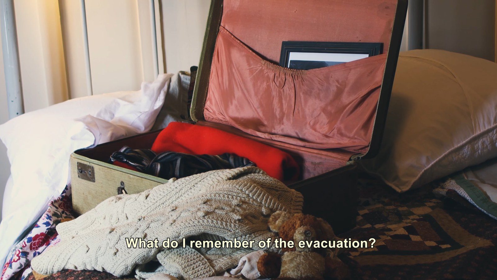 An open suitcase packed with clothes and a teddy bear, under the film's opening line